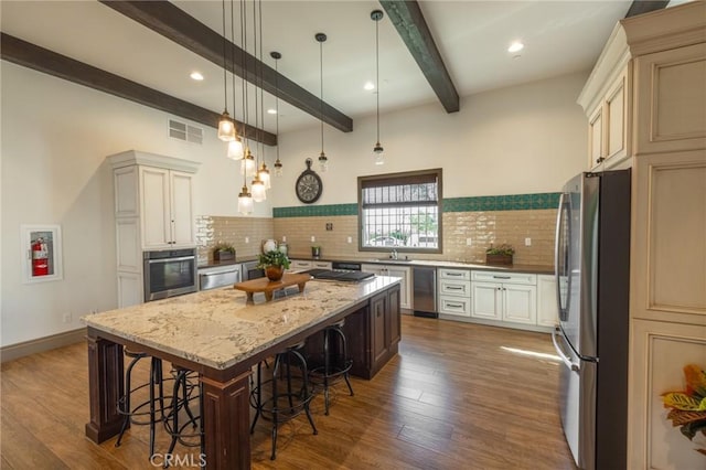 kitchen with stainless steel appliances, hanging light fixtures, a center island, dark wood-style floors, and a kitchen bar