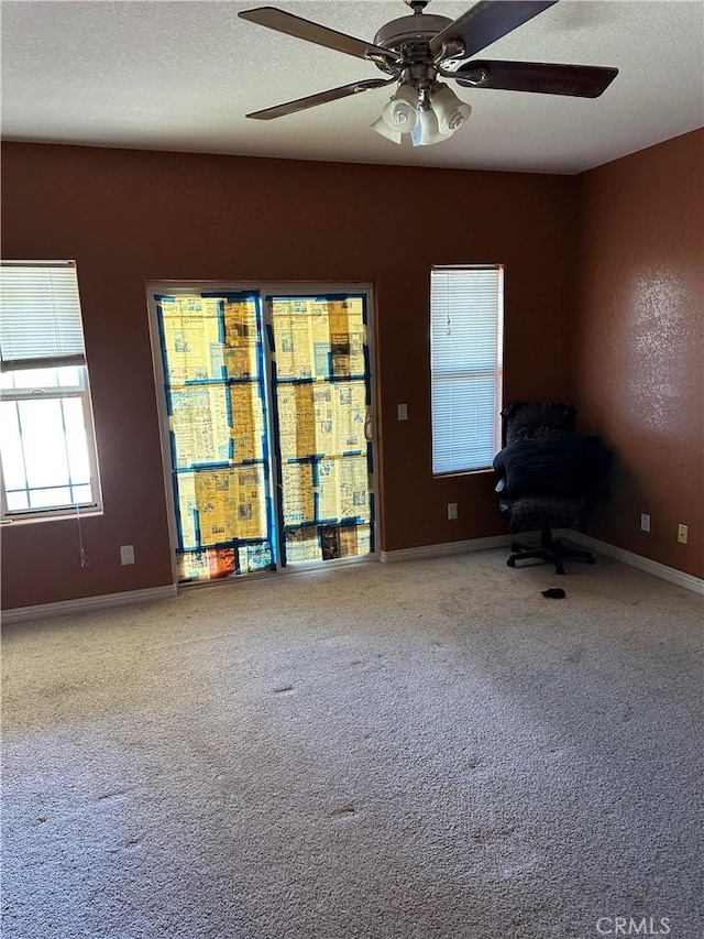 interior space featuring a ceiling fan, carpet flooring, a textured ceiling, and baseboards