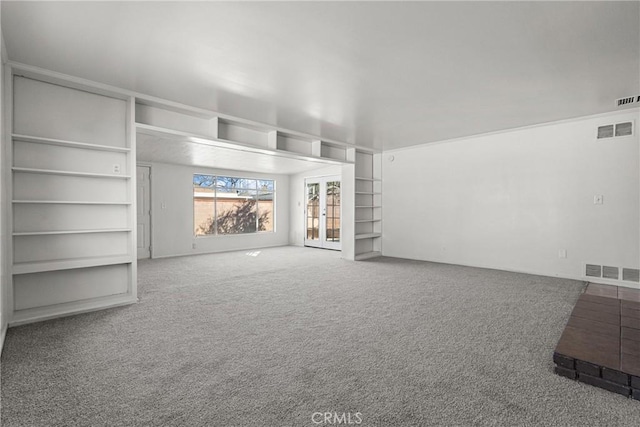 unfurnished living room featuring built in shelves, french doors, visible vents, and carpet flooring