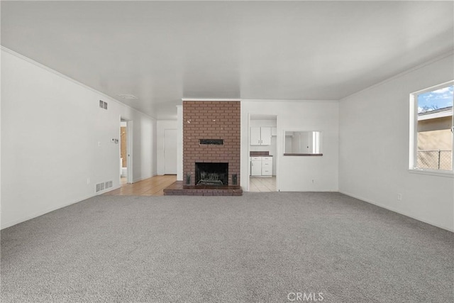 unfurnished living room featuring light carpet, ornamental molding, a fireplace, and visible vents