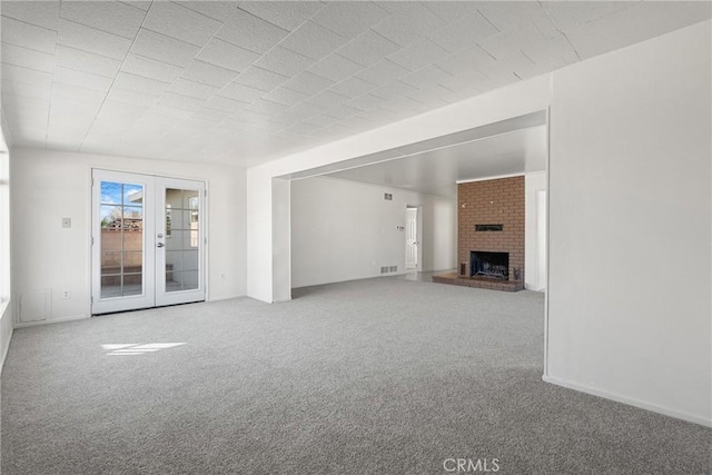 unfurnished living room with french doors, carpet flooring, a fireplace, and visible vents