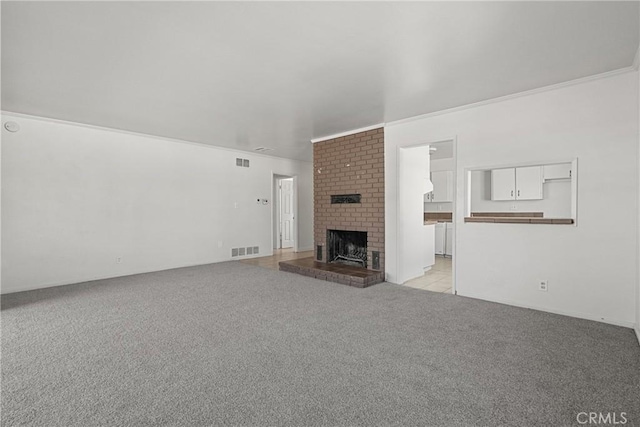 unfurnished living room with light carpet, a brick fireplace, and visible vents