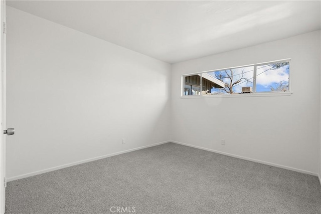 carpeted spare room featuring baseboards