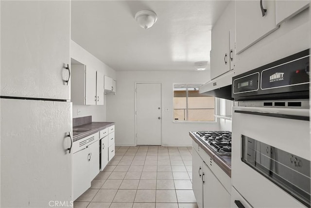 kitchen with light tile patterned floors, white cabinets, ventilation hood, white oven, and dark countertops