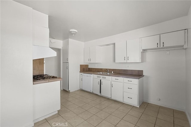 kitchen featuring dark countertops, white dishwasher, white cabinets, and a sink