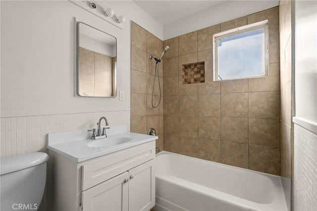 full bath featuring shower / washtub combination, a wainscoted wall, tile walls, toilet, and vanity