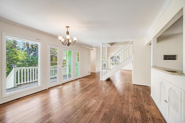 unfurnished dining area featuring stairs, hardwood / wood-style flooring, an inviting chandelier, and crown molding