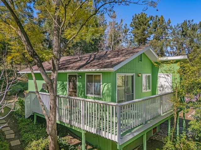 back of house with a deck and roof with shingles