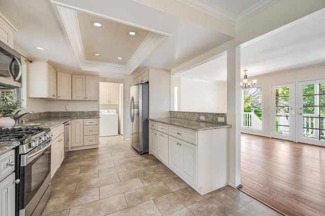 kitchen with cream cabinetry, washer / dryer, a notable chandelier, and stainless steel appliances