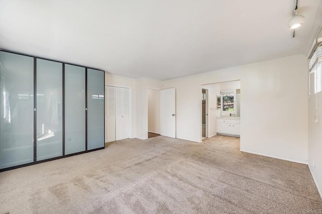 unfurnished bedroom featuring crown molding, connected bathroom, two closets, and carpet floors