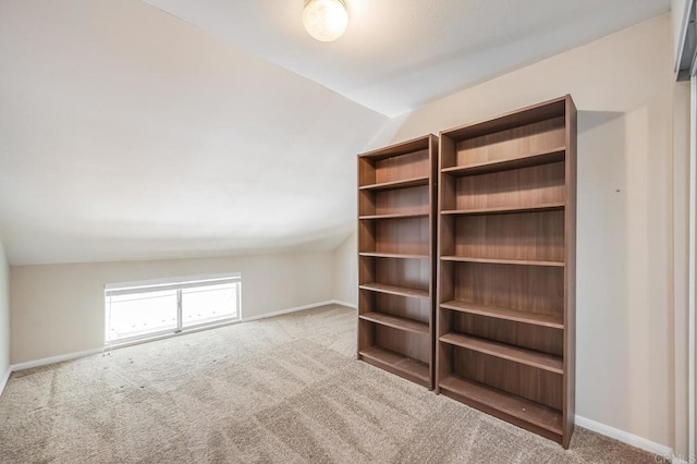 interior space featuring carpet flooring, baseboards, and lofted ceiling