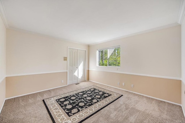 empty room featuring ornamental molding, baseboards, and carpet floors