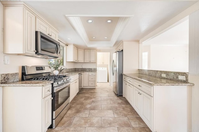 kitchen featuring recessed lighting, crown molding, a tray ceiling, stainless steel appliances, and a sink