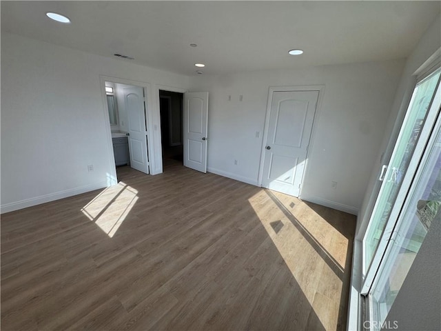 unfurnished bedroom with baseboards, visible vents, connected bathroom, wood finished floors, and recessed lighting