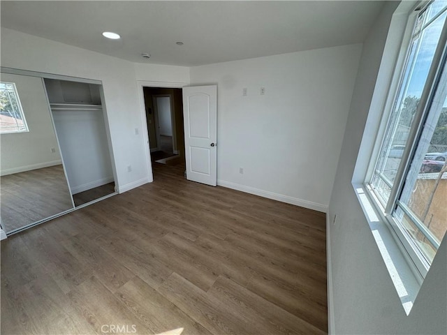 unfurnished bedroom featuring a closet, baseboards, and wood finished floors