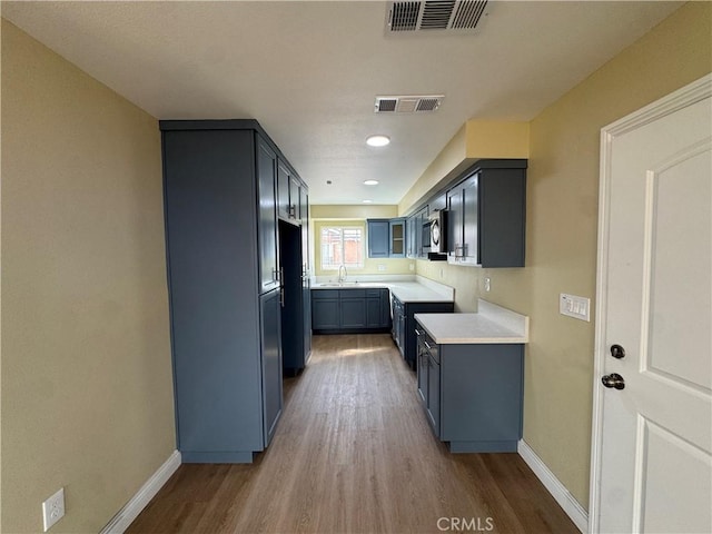 kitchen with visible vents, a sink, stainless steel microwave, and wood finished floors