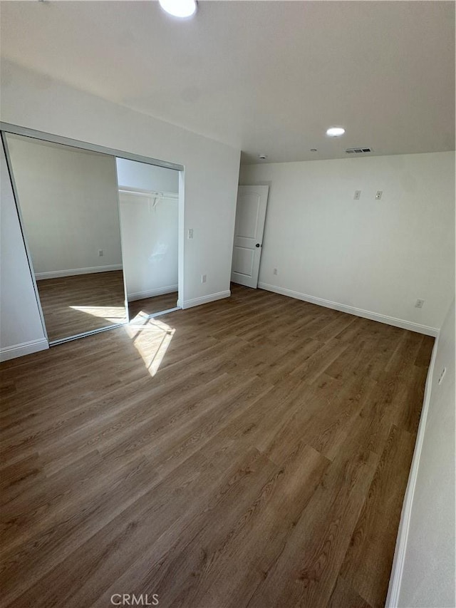 unfurnished bedroom featuring a closet, wood finished floors, visible vents, and baseboards