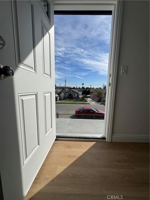 doorway to outside featuring baseboards and wood finished floors