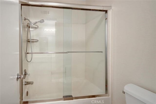 full bathroom with toilet and combined bath / shower with glass door