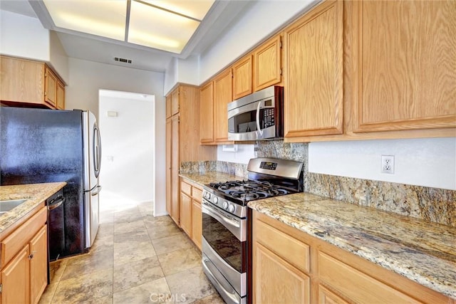 kitchen with light stone countertops, visible vents, appliances with stainless steel finishes, and light brown cabinetry