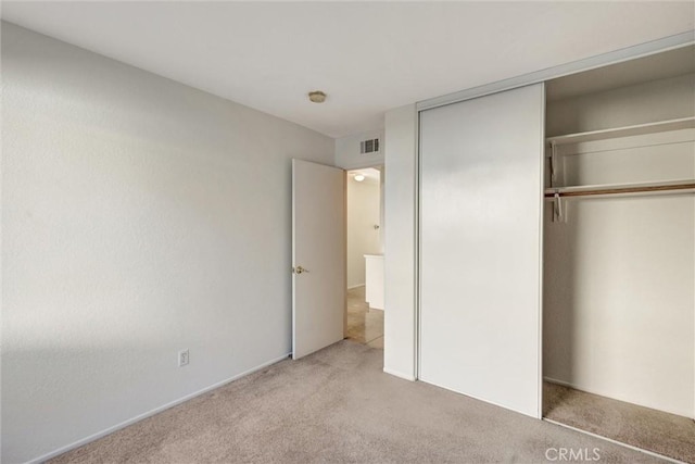 unfurnished bedroom with a closet, light carpet, and visible vents