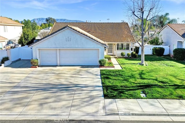 view of front facade with a mountain view, fence, driveway, stucco siding, and a front yard