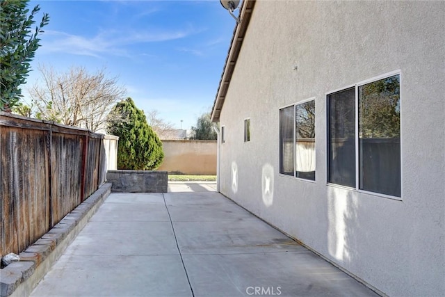 view of side of property featuring a patio area, a fenced backyard, and stucco siding