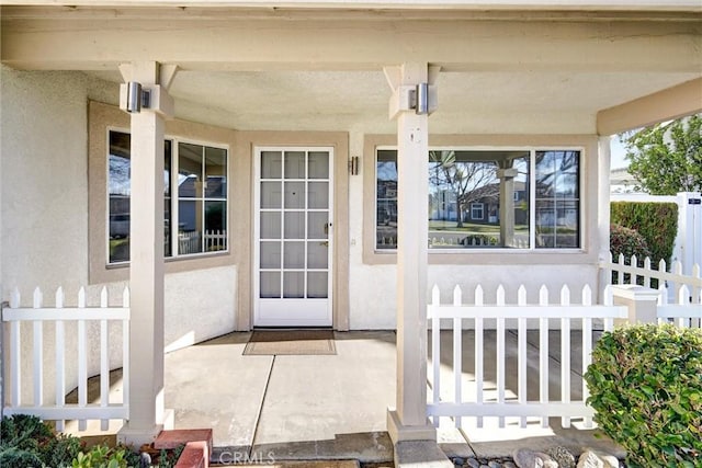 property entrance with fence and stucco siding