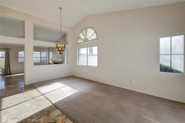 empty room with high vaulted ceiling, carpet, and an inviting chandelier