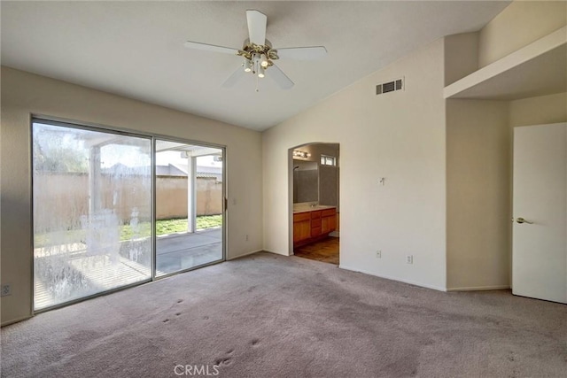 spare room featuring light carpet, visible vents, arched walkways, lofted ceiling, and ceiling fan