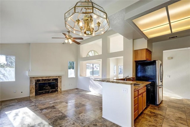 kitchen with a sink, visible vents, open floor plan, brown cabinets, and dishwasher