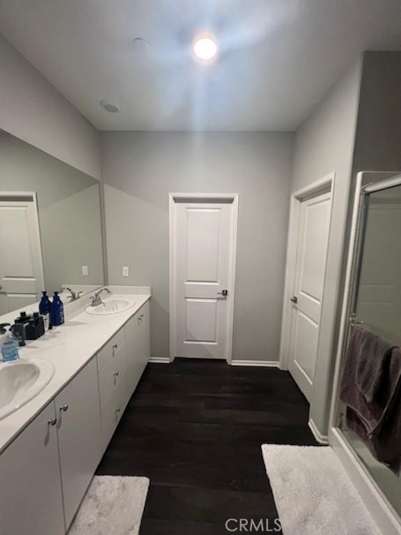 bathroom with double vanity, a sink, baseboards, and wood finished floors