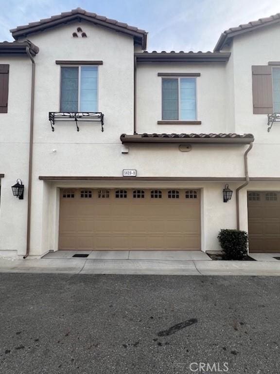 view of front of property featuring an attached garage, a tile roof, and stucco siding