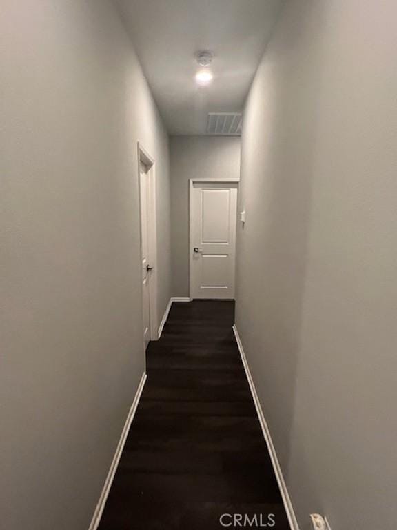 hallway featuring dark wood-style floors, baseboards, and visible vents