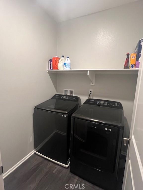 clothes washing area featuring laundry area, independent washer and dryer, dark wood finished floors, and baseboards