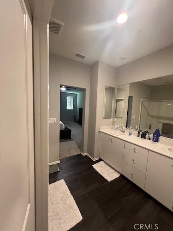 ensuite bathroom featuring double vanity, visible vents, ensuite bath, and wood finished floors