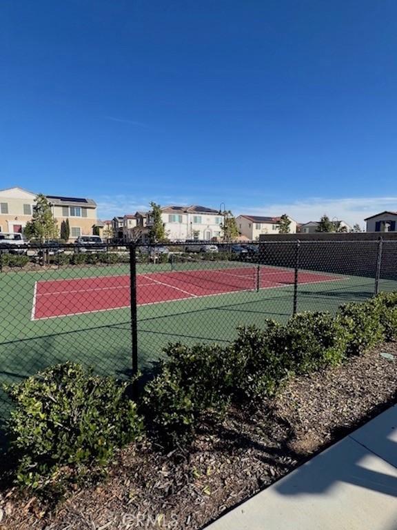 view of tennis court with fence and a residential view