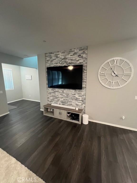 unfurnished living room with dark wood finished floors and baseboards