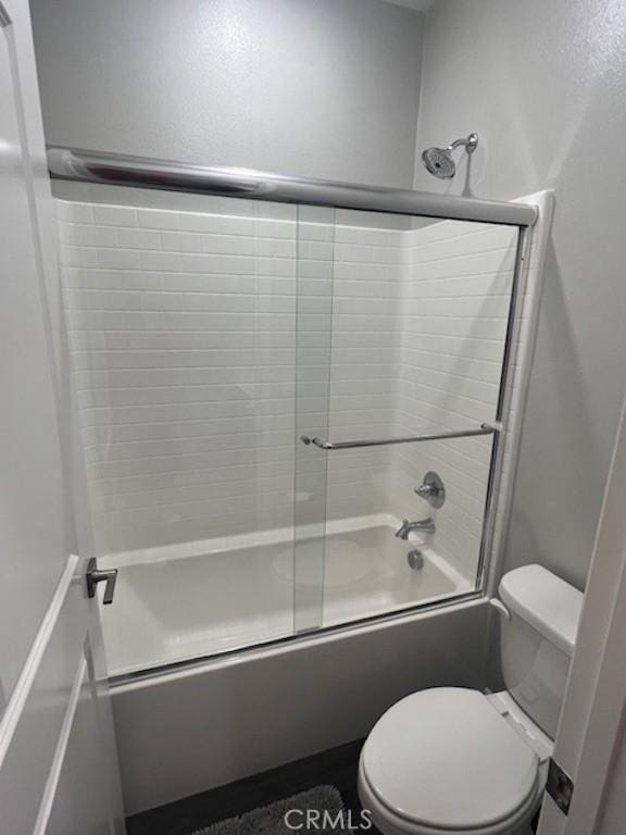 full bathroom with combined bath / shower with glass door and toilet