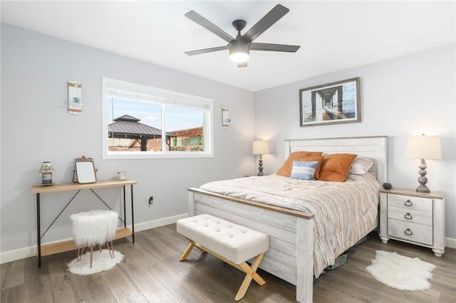 bedroom with dark wood-style floors, ceiling fan, and baseboards