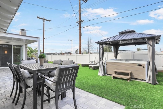 view of patio / terrace with a hot tub, a fenced backyard, and a gazebo