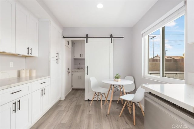dining room featuring a barn door and light wood-style flooring