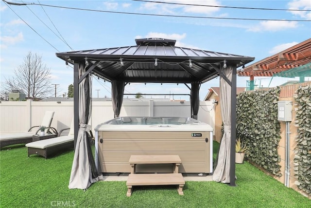 exterior space with a fenced backyard, a hot tub, and a gazebo