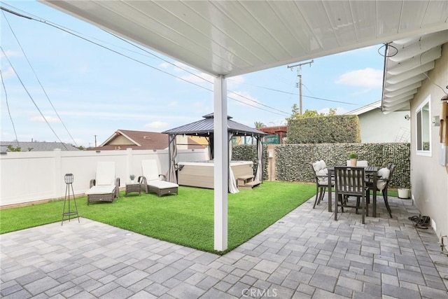 view of patio with a hot tub, outdoor dining area, a fenced backyard, and a gazebo