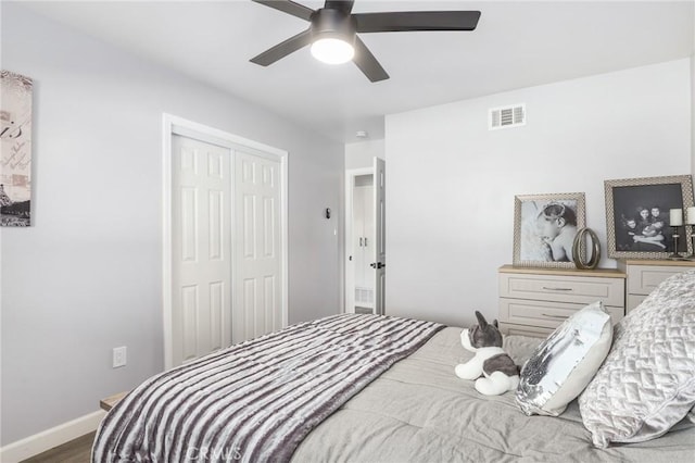 bedroom featuring a closet, visible vents, ceiling fan, wood finished floors, and baseboards