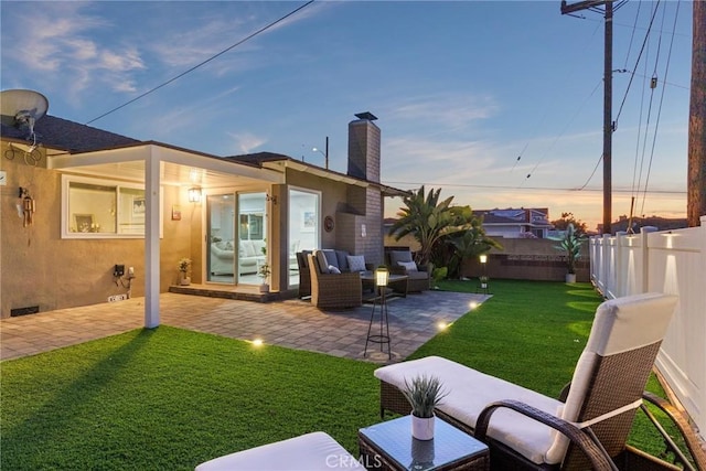 back of property featuring a yard, a patio, a chimney, an outdoor hangout area, and a fenced backyard