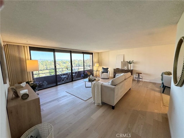 living room featuring light wood-style flooring, expansive windows, and a textured ceiling