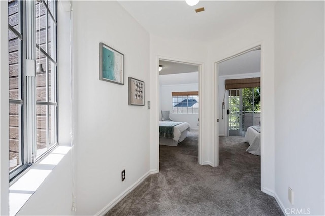 hallway with dark carpet and baseboards