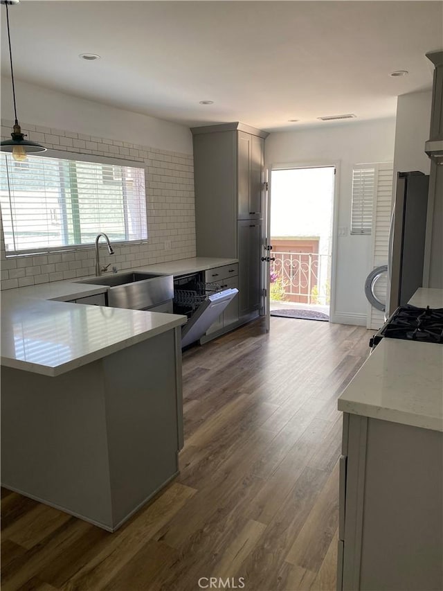 kitchen with light countertops, a sink, freestanding refrigerator, and gray cabinetry