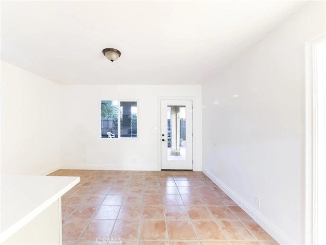 unfurnished room with light tile patterned floors and baseboards